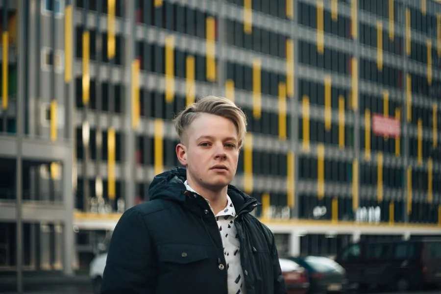 A young man in a dark coat on a city street