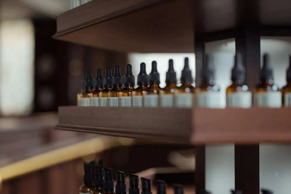 Rows of small amber bottles on a wooden shelf